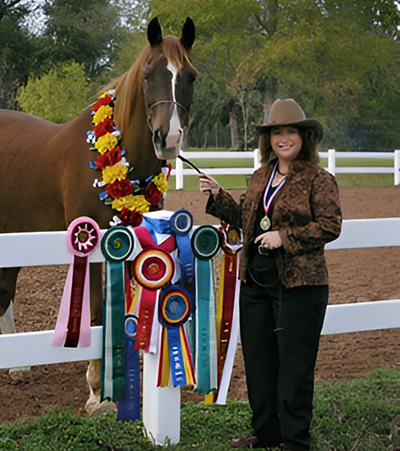 Woman with award-winning horse and ribbons.